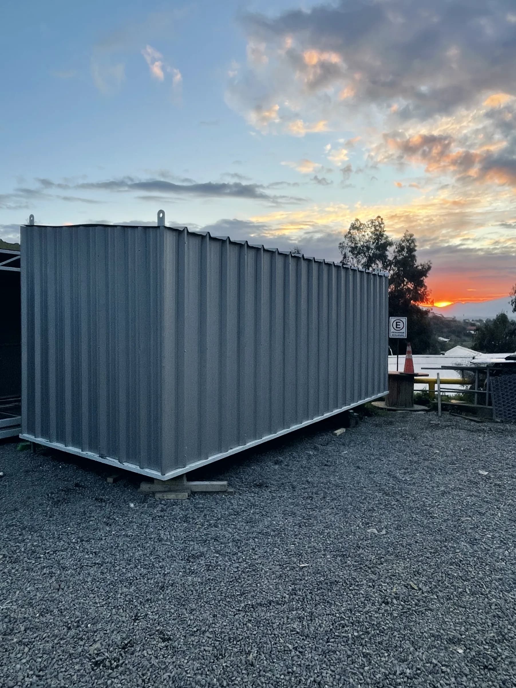 Bodega modular terminada con revestimiento metálico, al atardecer