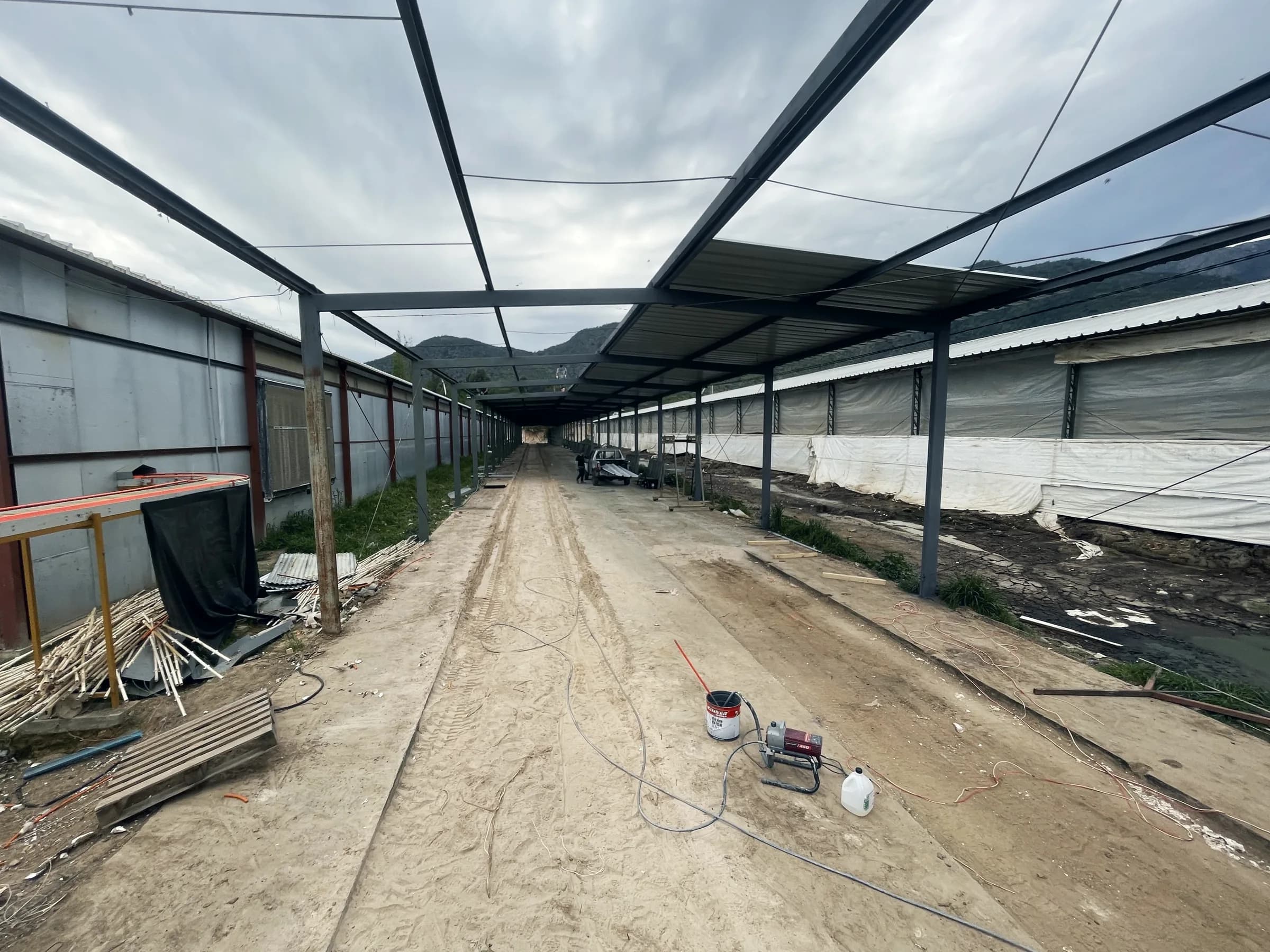 Equipo de pintura airless y tarro de pintura en el piso del pasillo, bajo la estructura metálica
